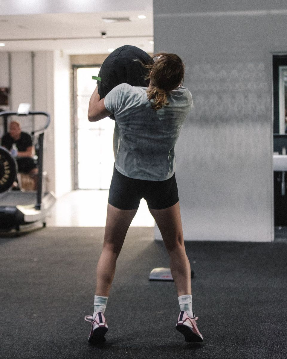 Jess throwing a 88 lb sandbag over her shoulder